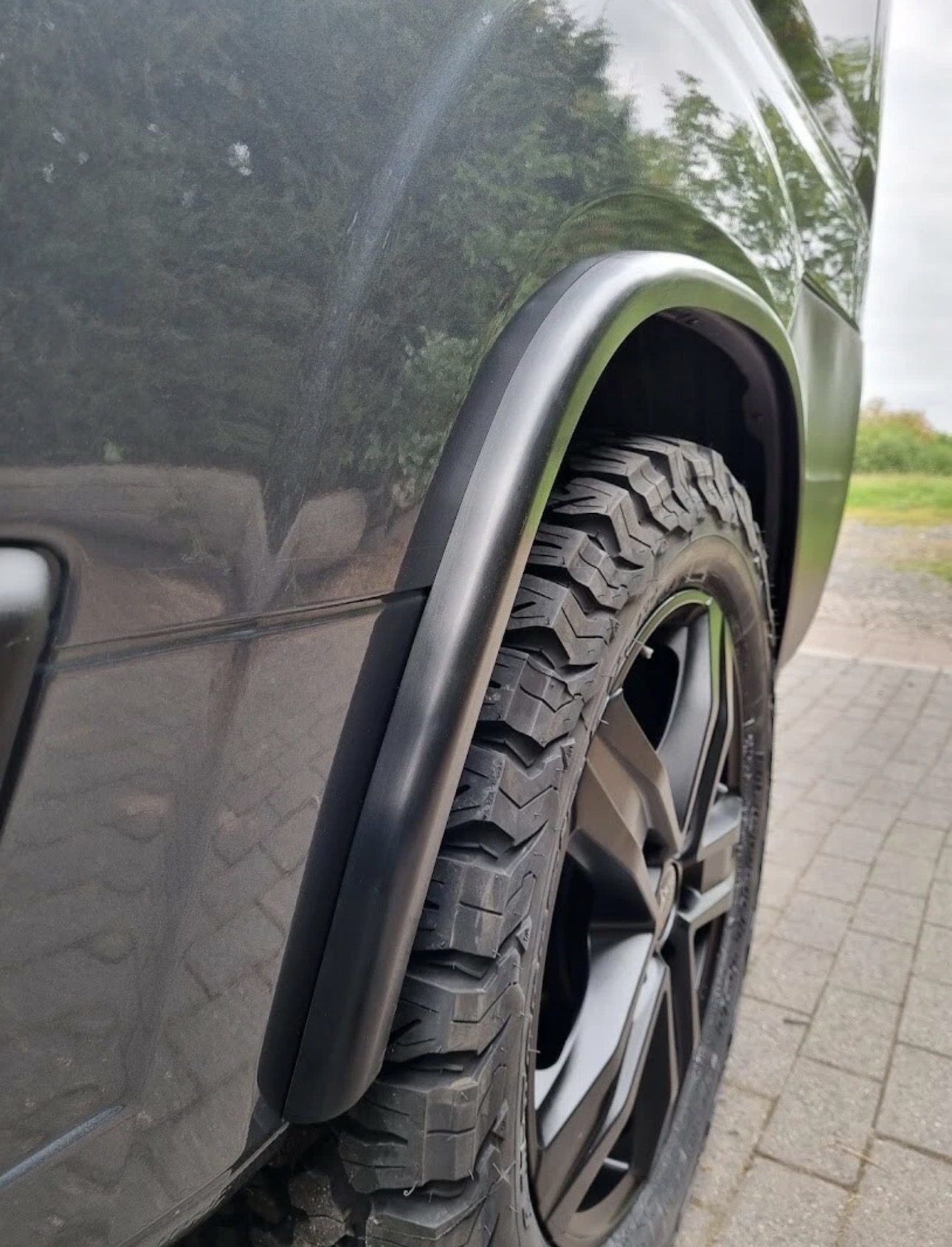 Extended matte black wheel arch over an all-terrain tyre on a lifted van